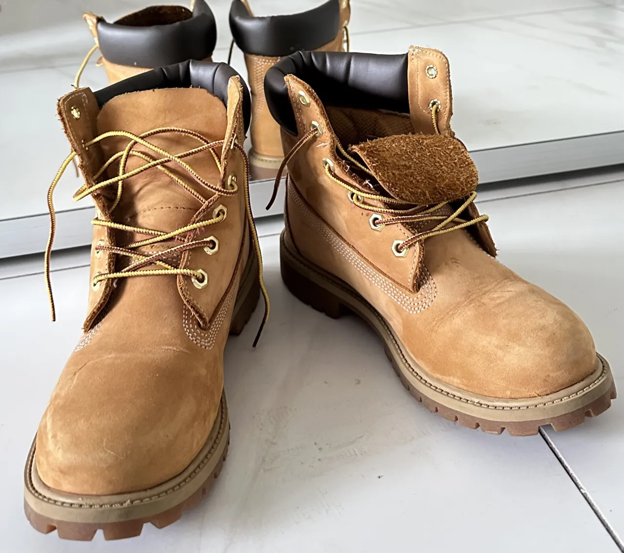 Botas de cuero color suela con cordones amarillos y detalles en marrón. Caña alta con cuello acolchado.