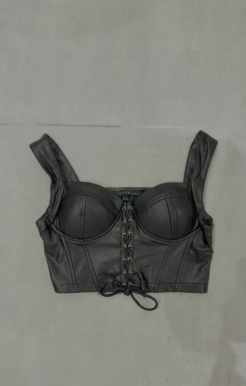 Top corset de cuero sintético negro, con ajuste frontal de cordones y tiras anchas. Ideal para looks de fiesta o salidas.