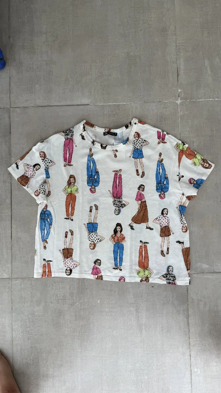 Remera de mujer con estampado de figuras femeninas en diferentes poses y vestimentas. Ideal para un look casual y moderno.