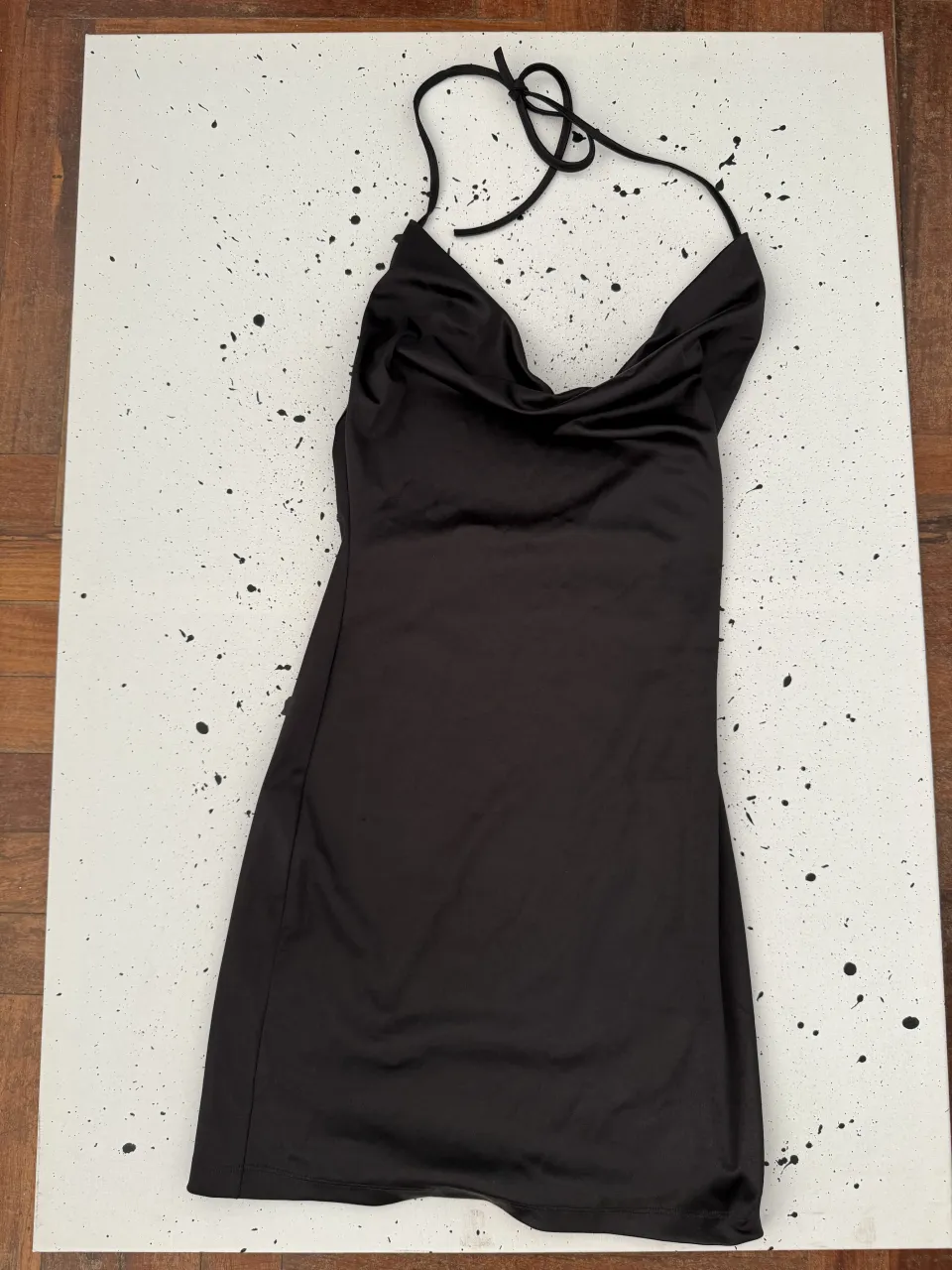 Vestido negro corto con tiras finas que se anudan en el cuello.