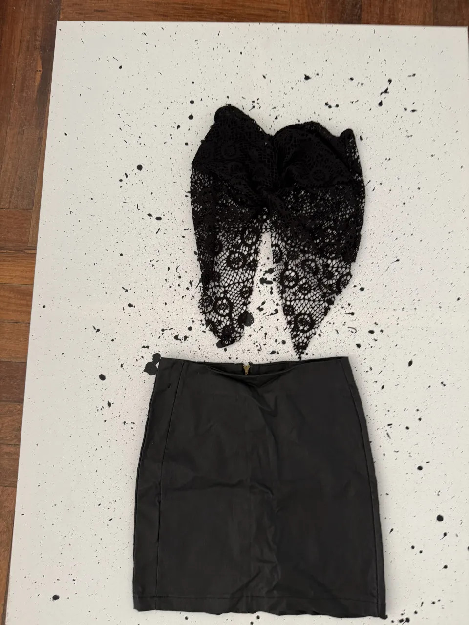 Pollera negra corta de cuero sintético con cierre dorado. La parte superior es un detalle de encaje negro.