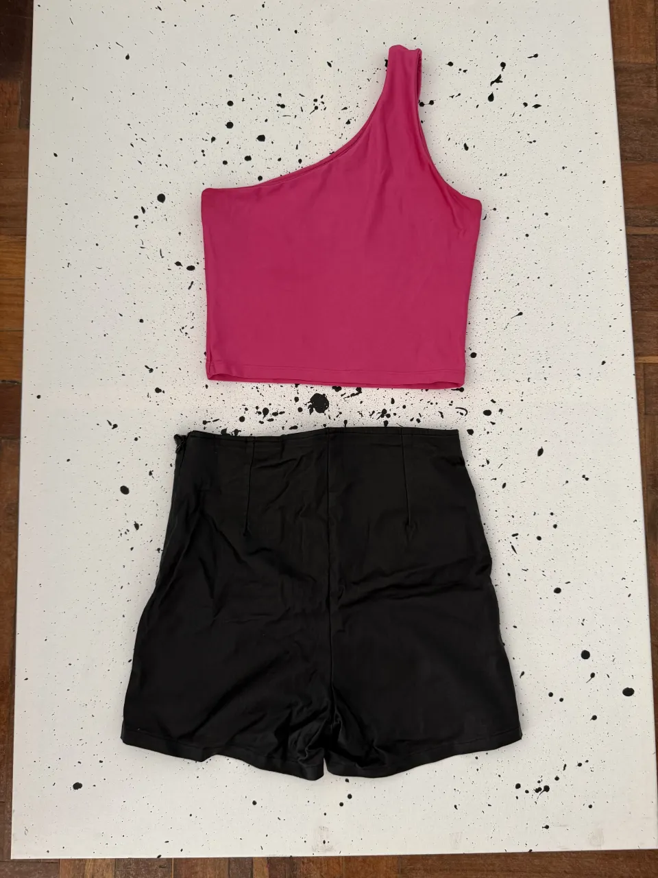 Conjunto de top asimétrico color fucsia y shorts tiro alto negros.