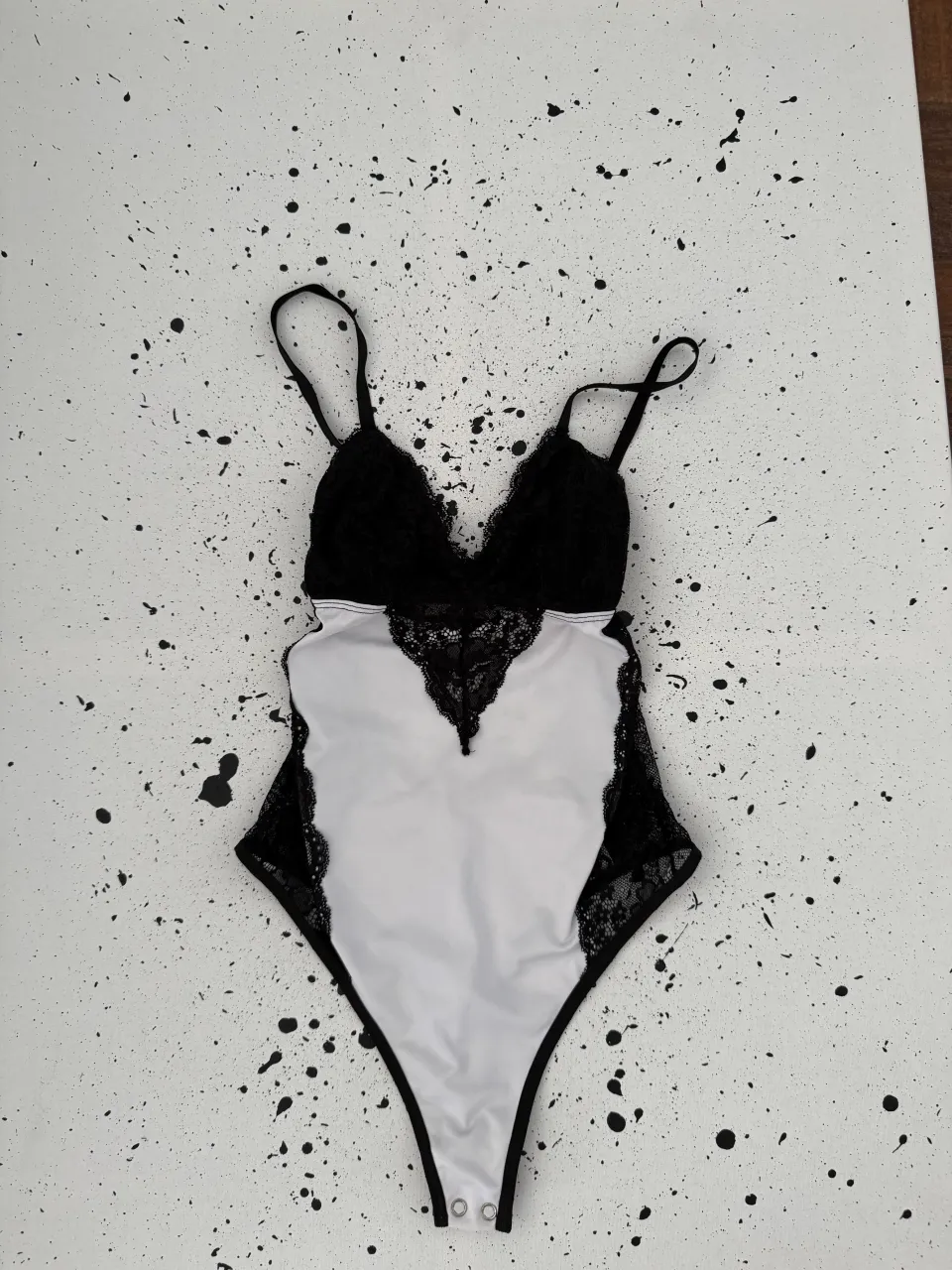 Body de encaje negro y tela blanca. Breteles finos regulables. Escote en V con detalle de encaje. Espalda descubierta con tiras.