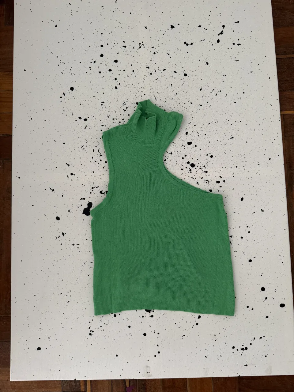 Musculosa verde con cuello alto y recorte asimétrico en el hombro.