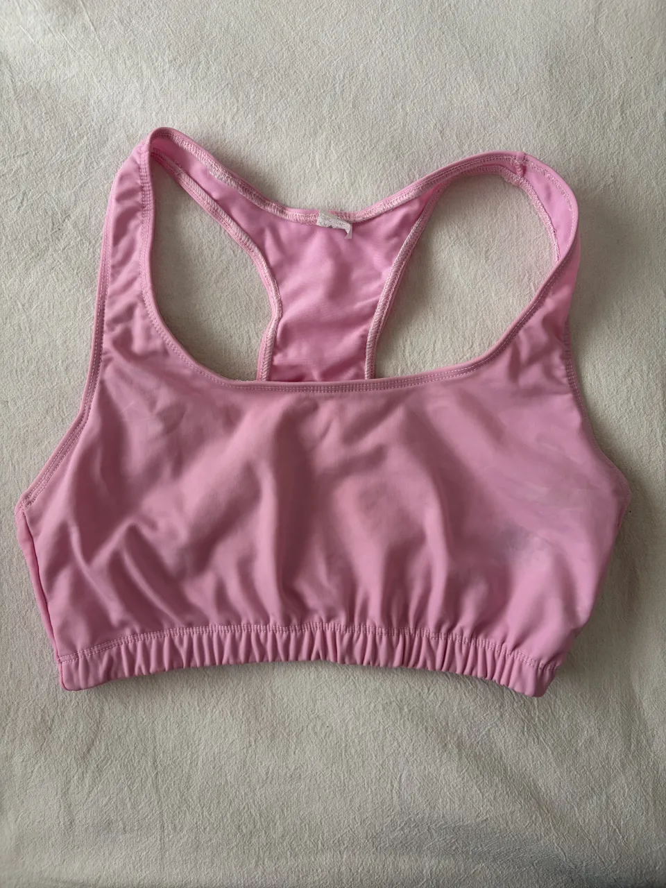 Corpiño deportivo rosa con tiras tipo racerback y elástico en la base.