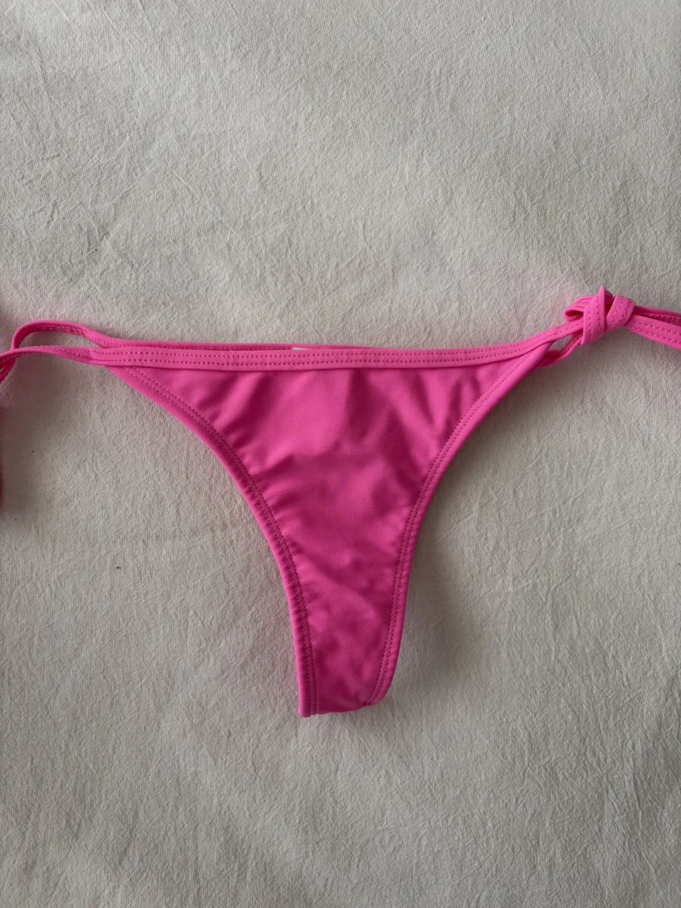 Bombacha de traje de baño color rosa con tiras laterales para atar.