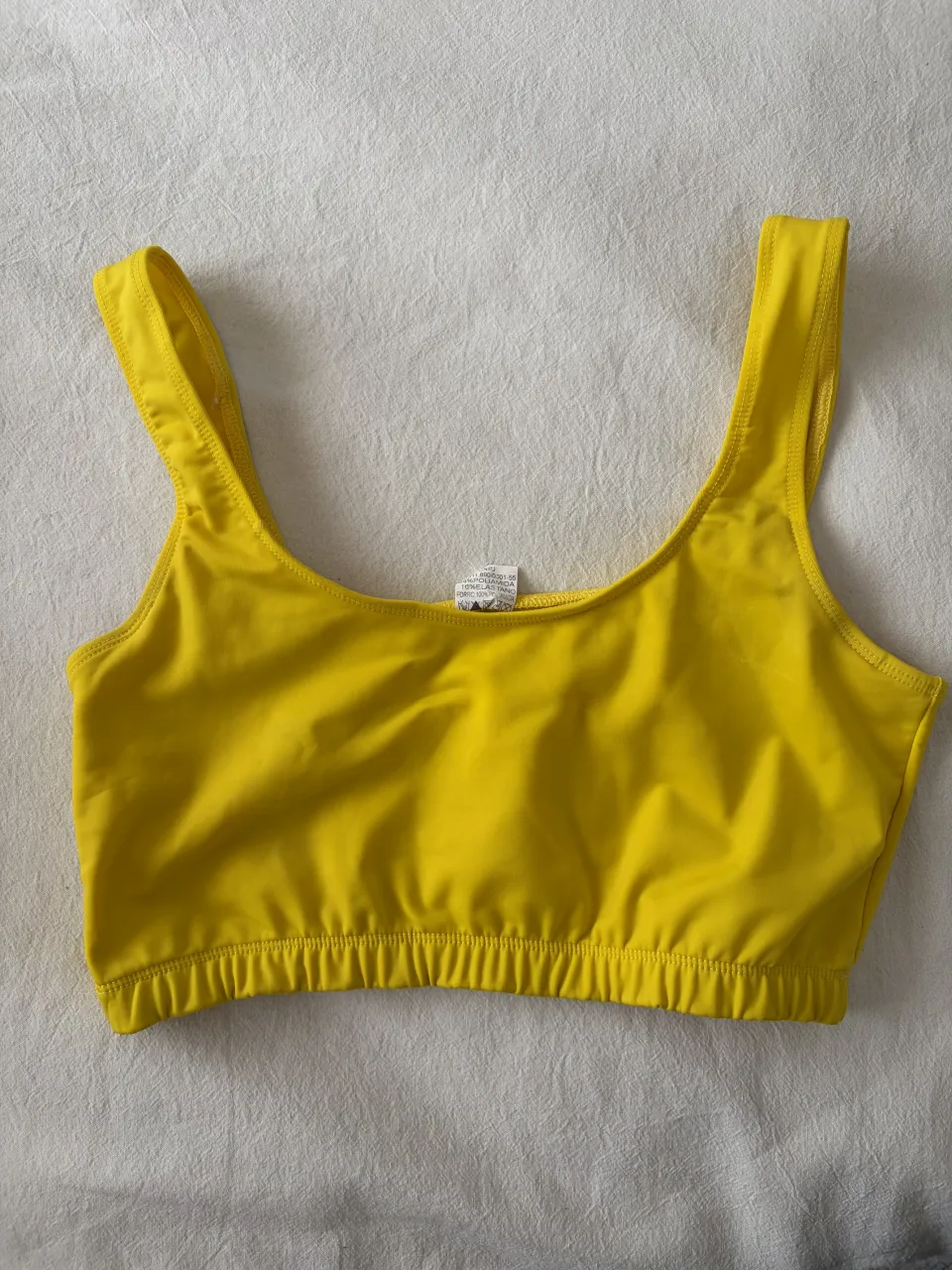 Top deportivo amarillo con elástico en la base.