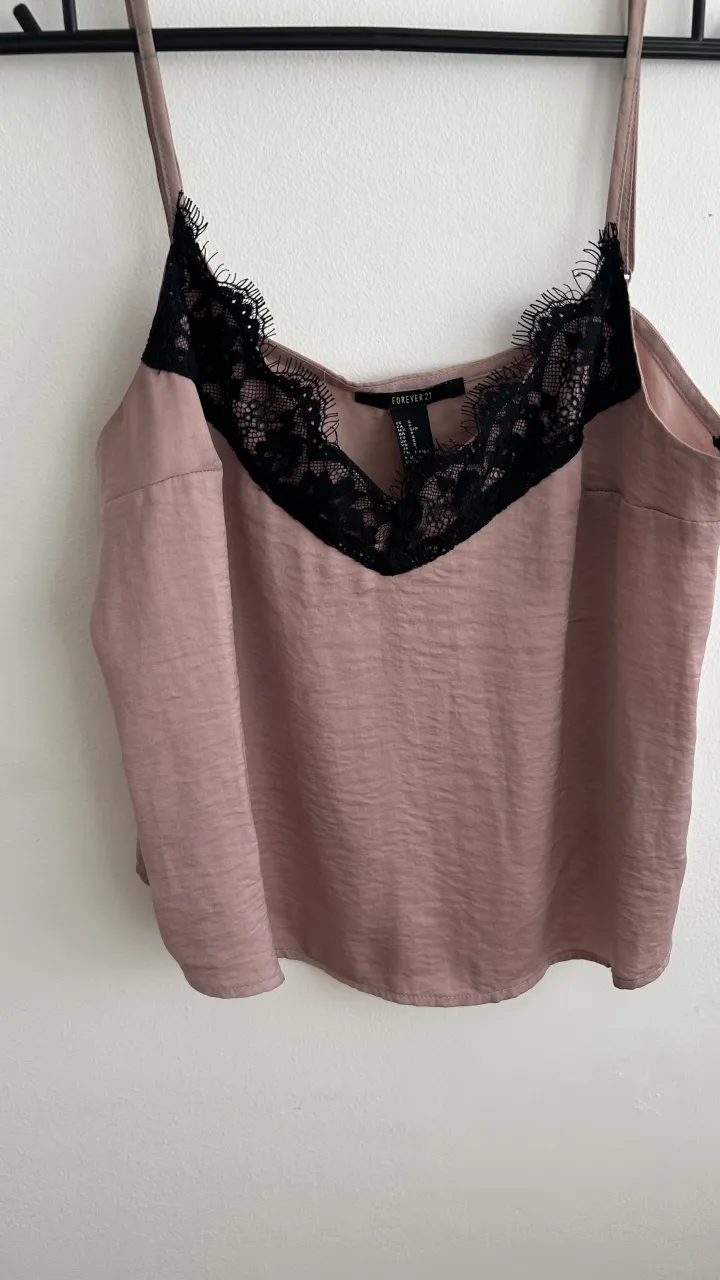 Top de seda color rosa pálido con detalles de encaje negro en el escote.