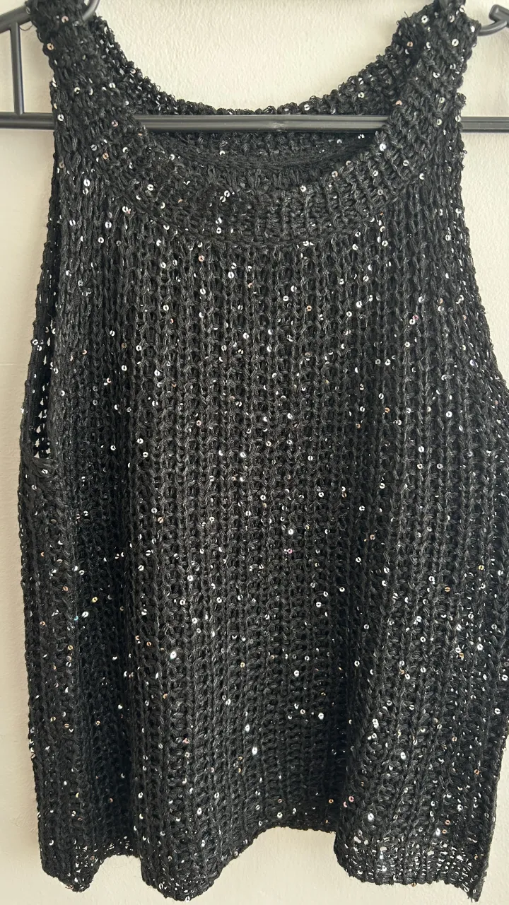 Musculosa negra tejida con lentejuelas plateadas.