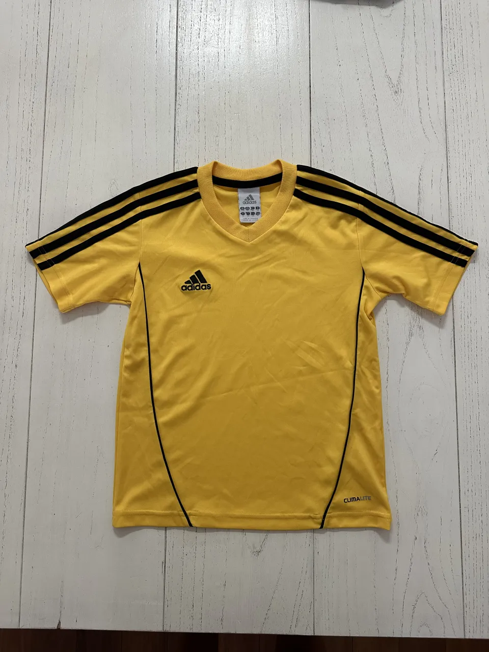 Remera deportiva amarilla con detalles negros en cuello y mangas. Logo de Adidas en el frente.