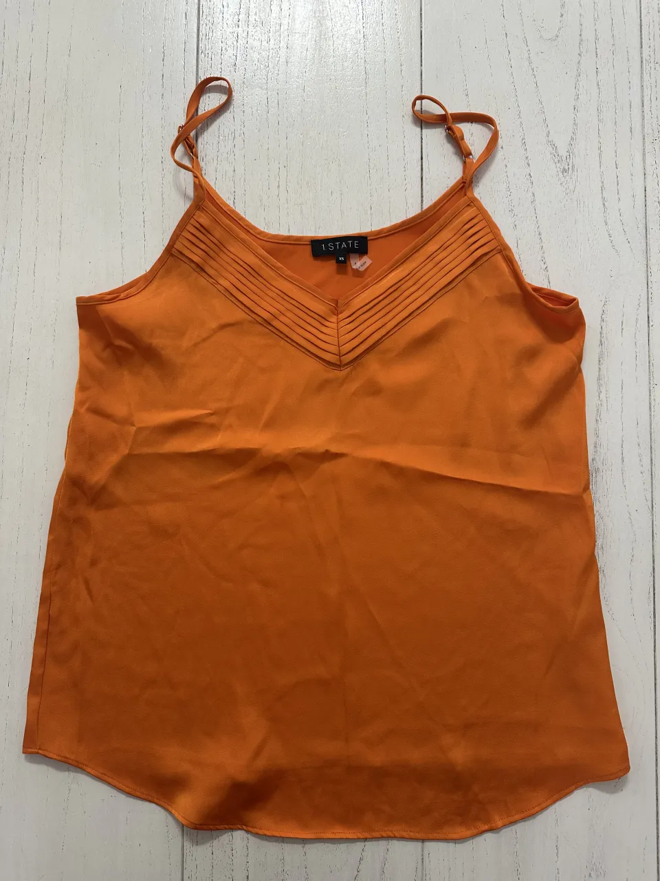 Top naranja con breteles finos y escote en V con detalles de pliegues.