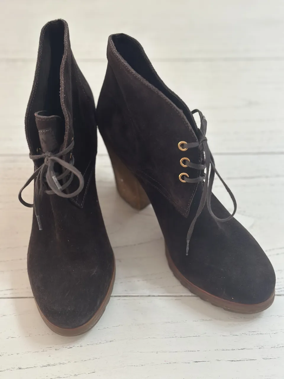 Botitas de gamuza color marrón oscuro con cordones y ojales dorados. Taco de madera grueso.