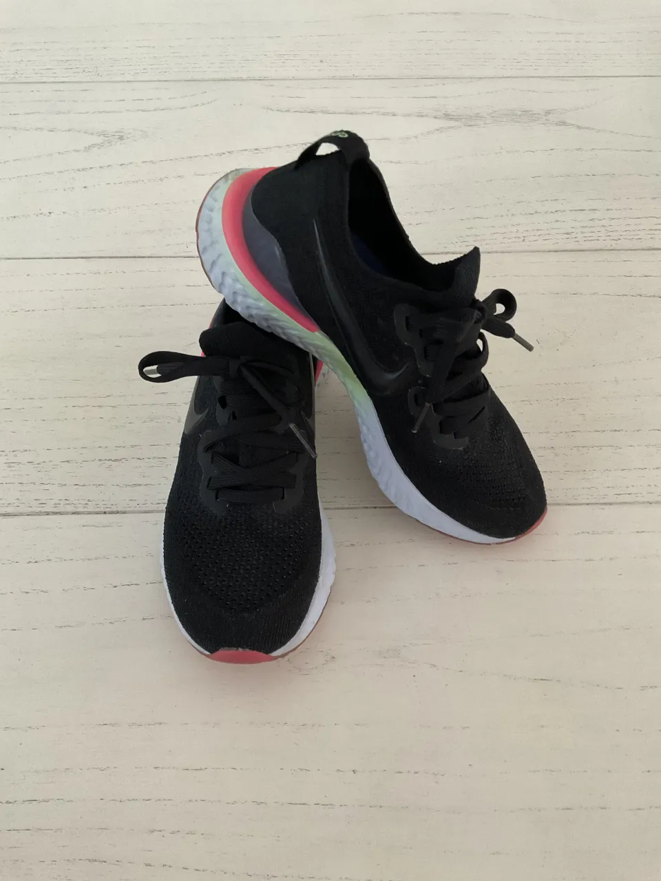 Zapatillas deportivas Nike negras con detalles en rosa, verde y celeste en la suela y el talón. Cordones negros.