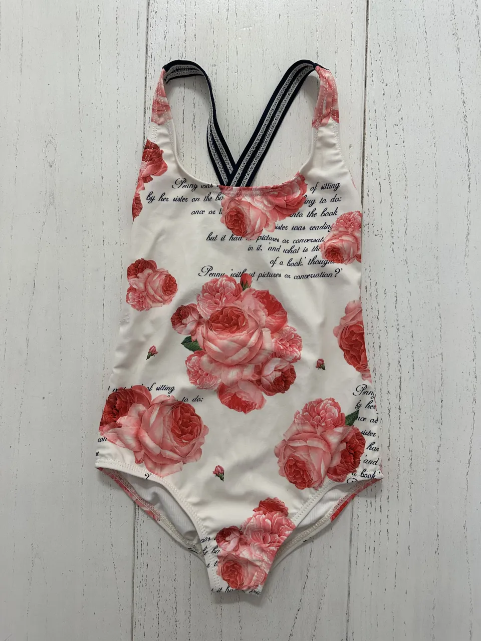 Enterito de baño blanco con estampa de rosas rojas y texto. Breteles cruzados en la espalda.