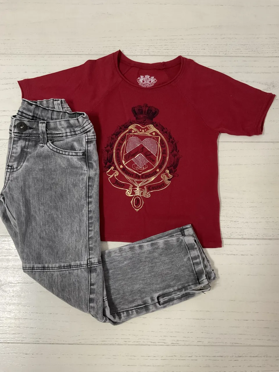 Conjunto de remera roja con escudo dorado y pantalón de jean gris. Ideal para un look casual y canchero.