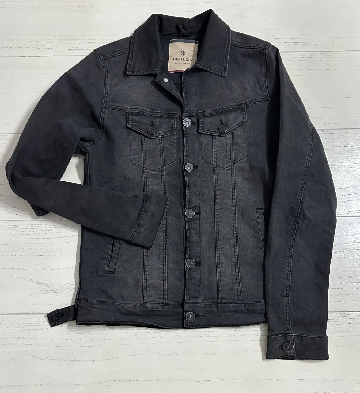 Campera de jean negra con botones al frente y bolsillos en el pecho.