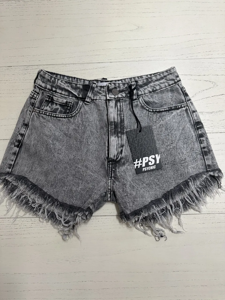 Shorts de jean grises con roturas y flecos en el ruedo. Poseen bolsillos delanteros y traseros.