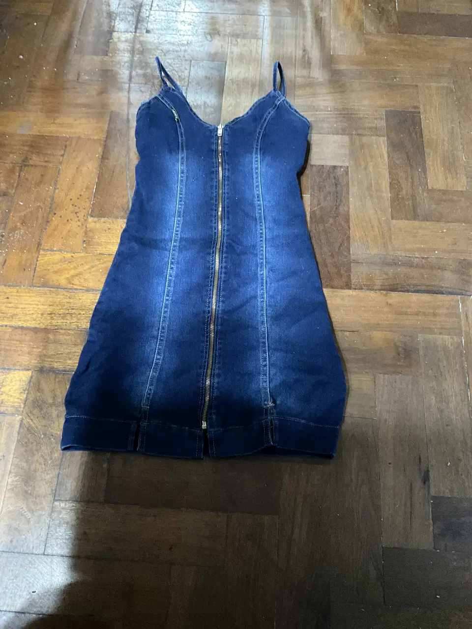 Vestido mini de jean azul con cierre frontal y tiras finas. Ideal para un look casual y moderno.