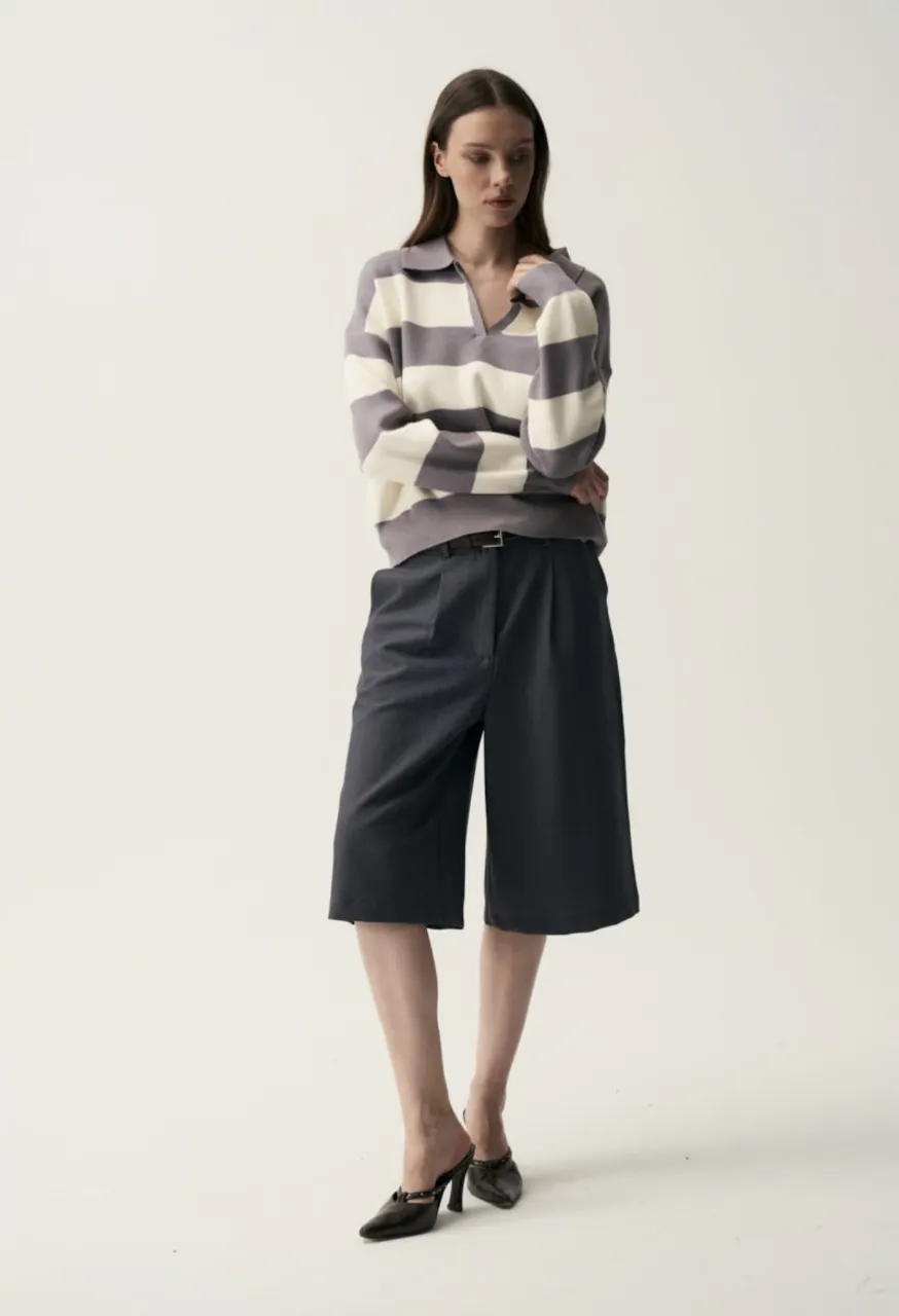 Pantalón culotte de color gris oscuro con pinzas y cinturón fino. Bermuda de sastrería, modelo jorts, estructurada y con cinturón marrón. Muy buen calce y estilo moderno.