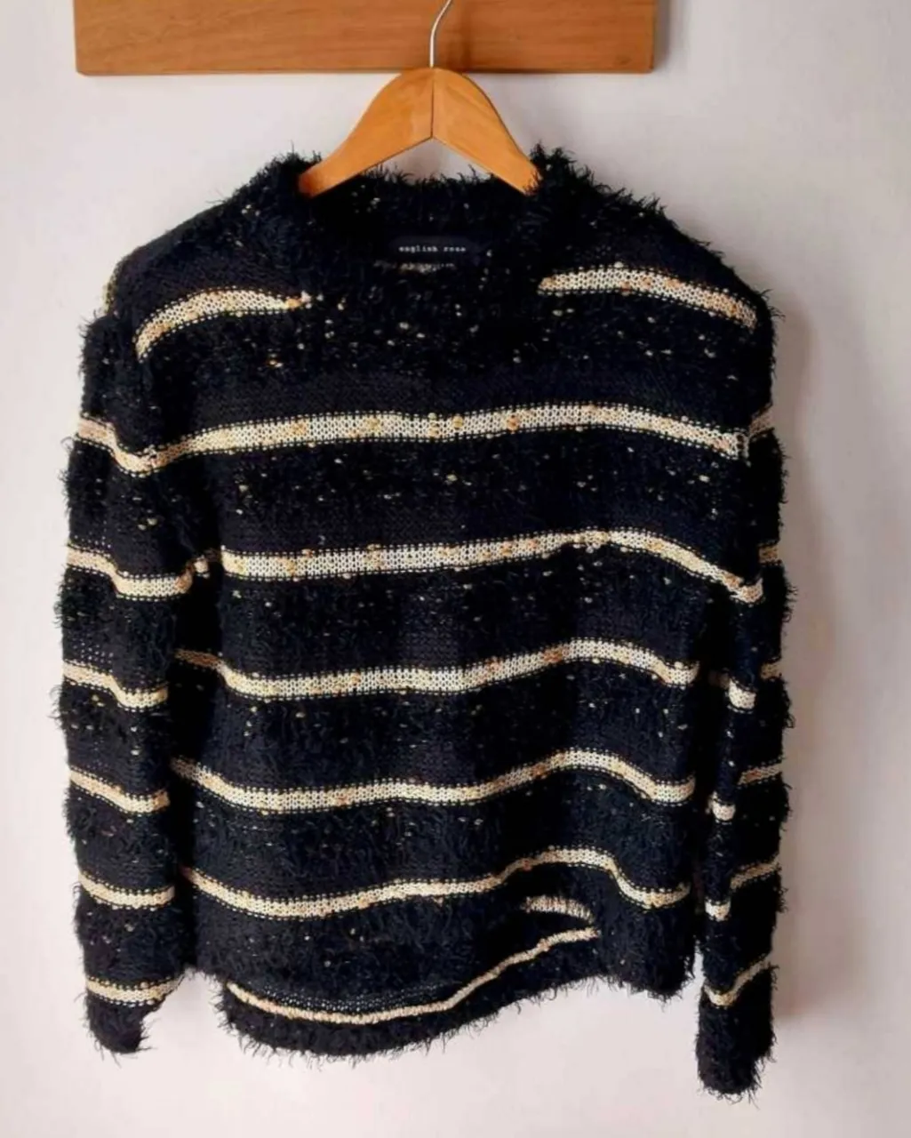 Sweater negro con rayas horizontales blancas y detalles dorados. Posee textura tejida con hilos y pintas en dorado.mide largo60atras 58adelante de ax.a ax.52cm.