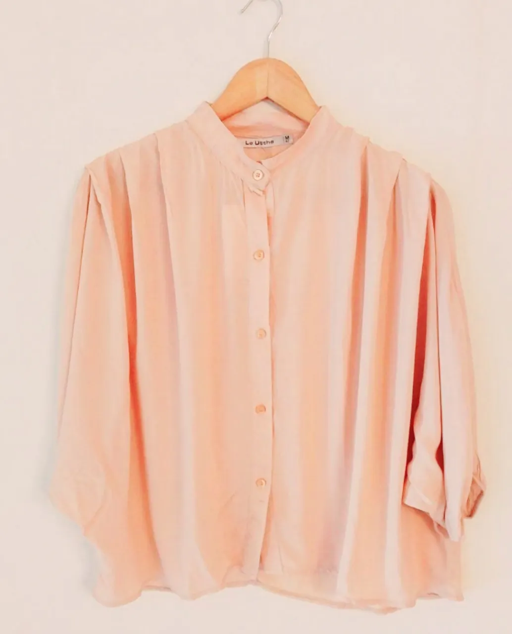 Blusa color rosa viejo, con cuello mao y mangas 3/4. Posee botones al frente y detalles sutiles en los hombros. Ideal para un look elegante y casual.