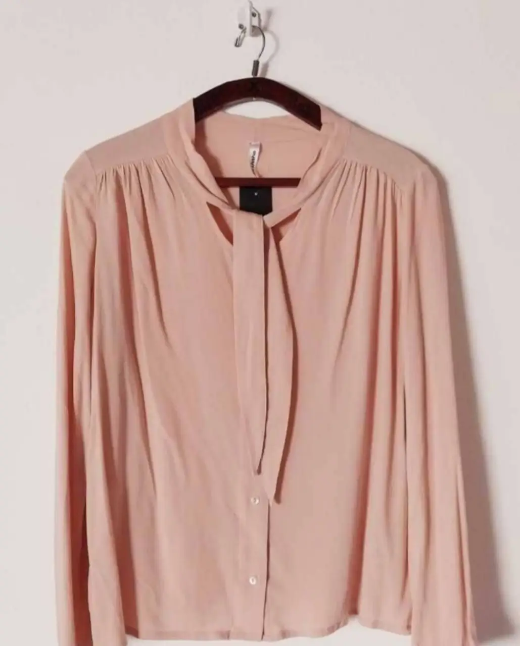 Blusa rosa con cuello alto y lazo, ideal para un look elegante y femenino. Perfecta para combinar con pantalones de vestir o faldas.