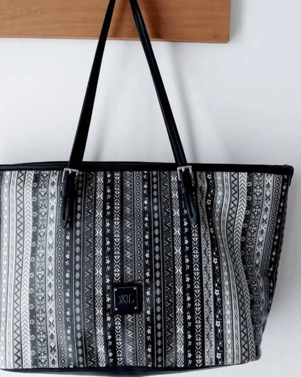 Bolso tote XL con estampado geométrico en blanco y negro. Ideal para llevar todo lo que necesitas con estilo. Cuenta con manijas negras y detalles metálicos.