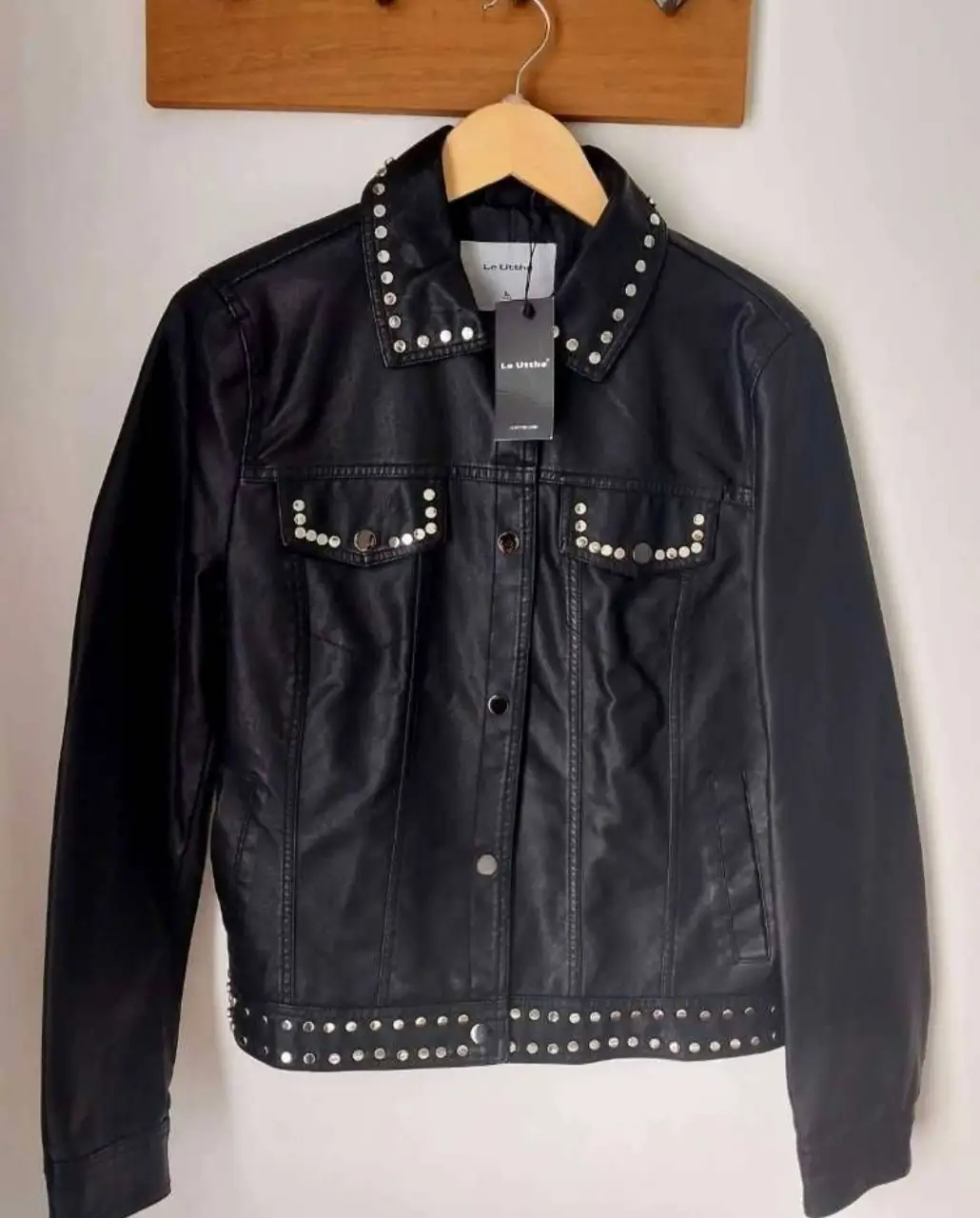 Campera biker de cuero sintético negra con tachas plateadas en cuello, bolsillos y bajo. Un clásico con un toque rockero para un look audaz.