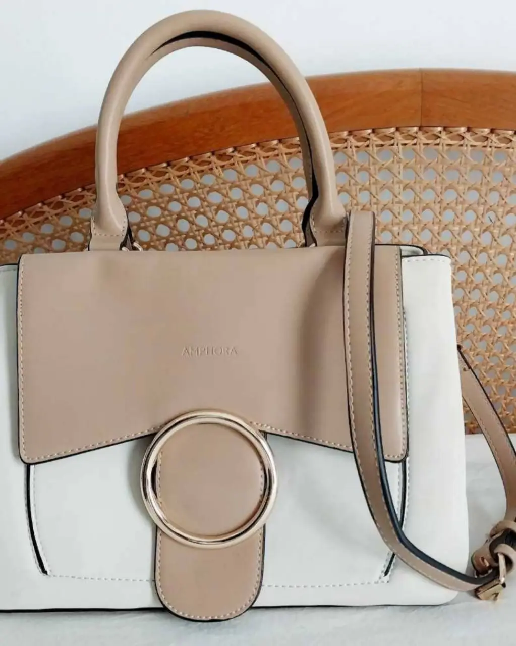 Cartera Amphora de hombro, con diseño bicolor en blanco y beige. Detalles dorados y un gran aro como cierre. Ideal para un look casual y elegante.