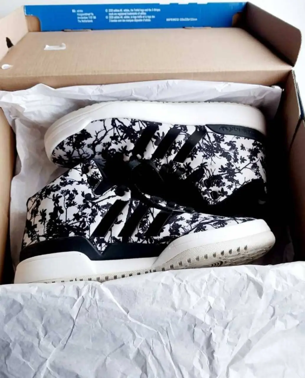 Zapatillas Adidas con estampado floral en blanco y negro. Diseño moderno y cómodo, ideales para un look casual y urbano.plantilla 24cm,solo un uso.envio en caja.