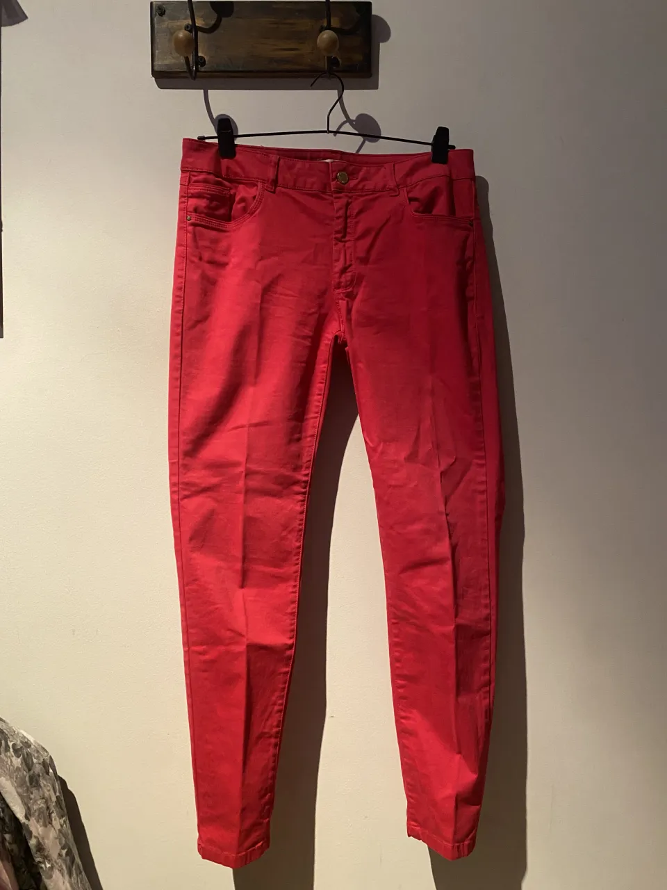 Pantalón de jean color rojo. Cierre con botón dorado y bolsillos delanteros y traseros.