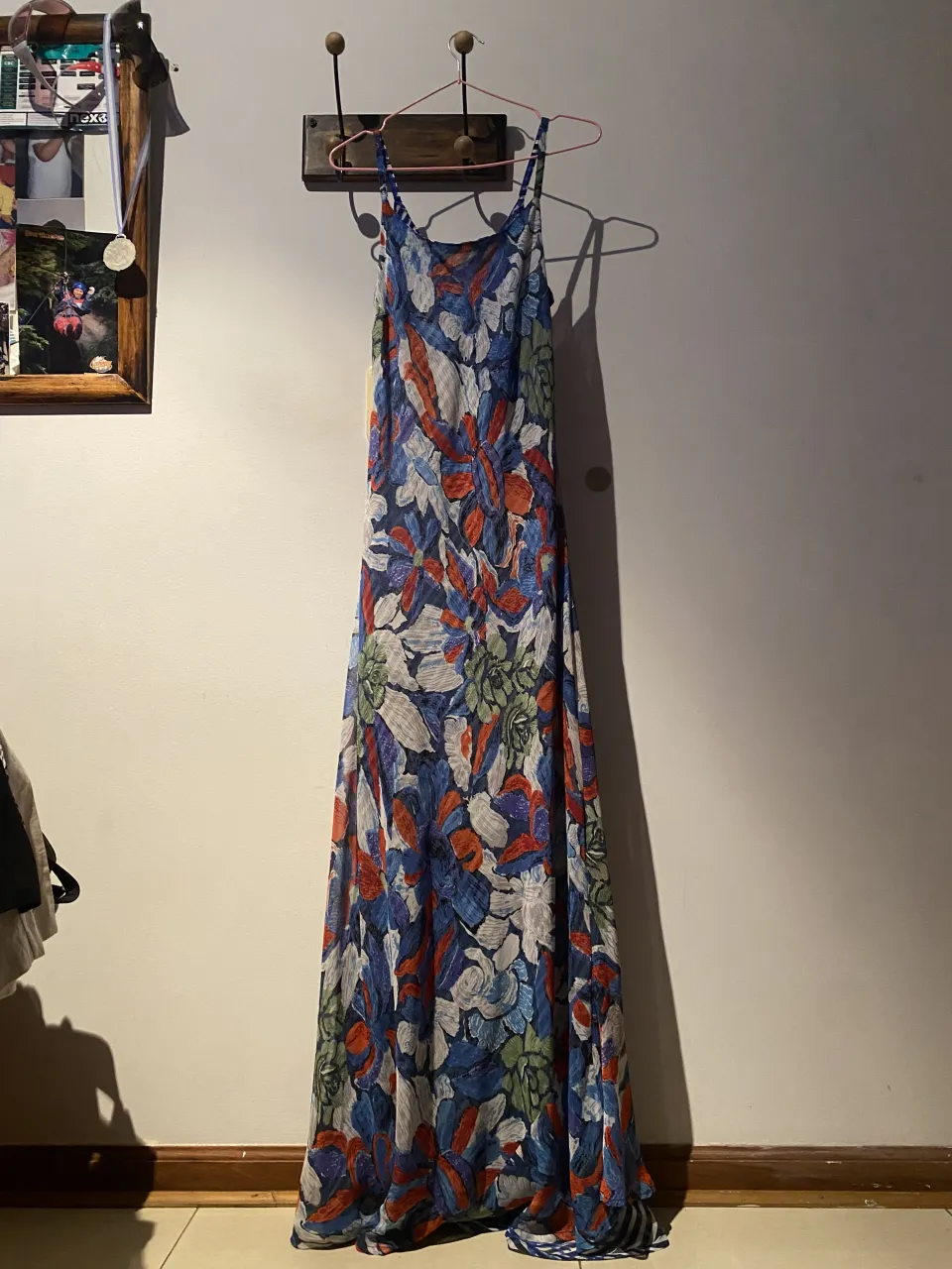 Vestido largo estampado con breteles finos. Posee un estampado floral en tonos azules, rojos, blancos y verdes.