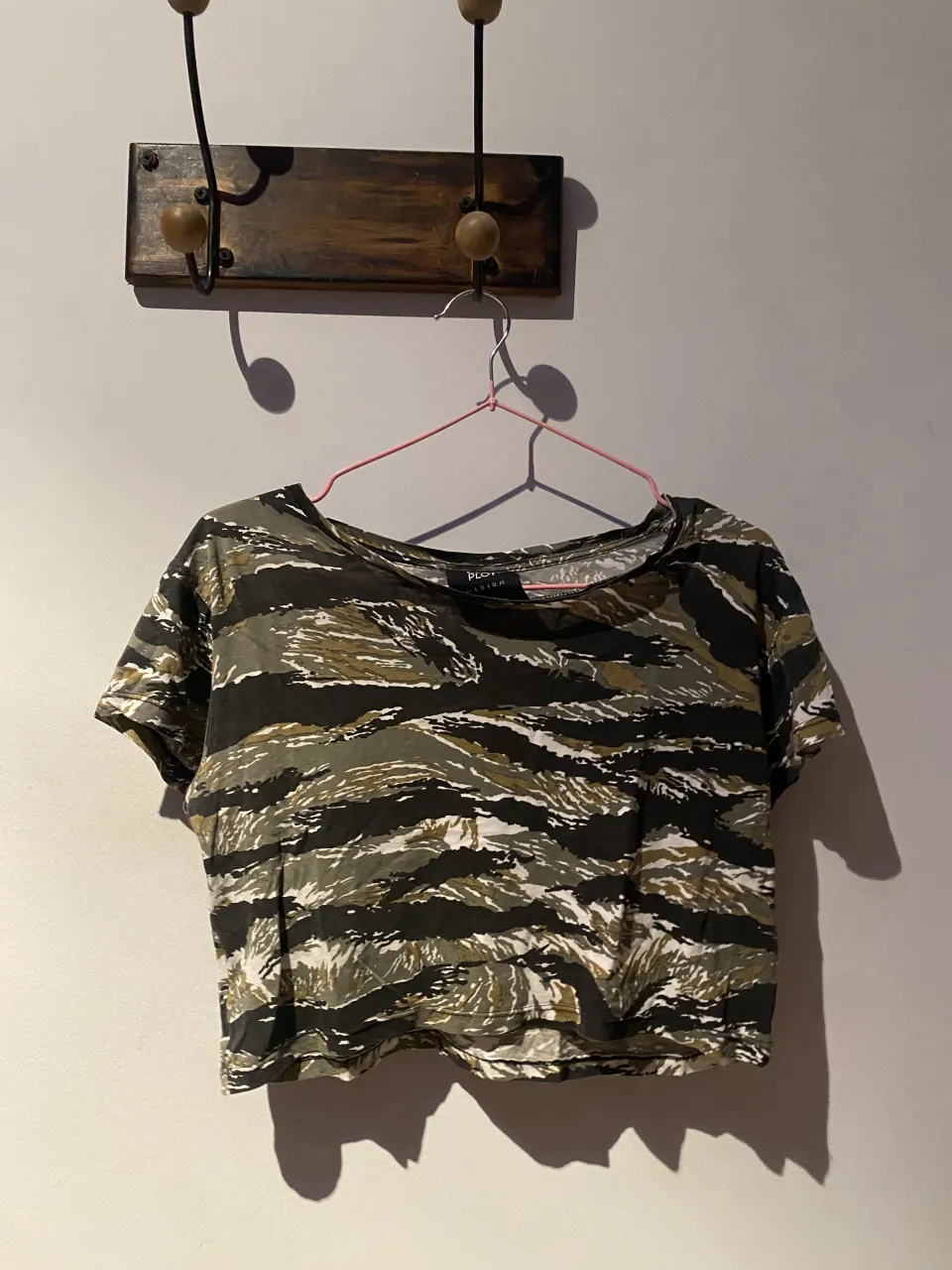 Remera manga corta con estampa camuflada en tonos verdes, negros y blancos.
