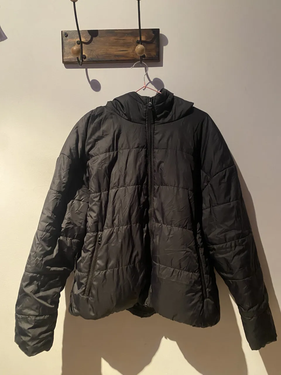 Campera negra acolchada con capucha y cierre completo. Posee bolsillos frontales con cierre.