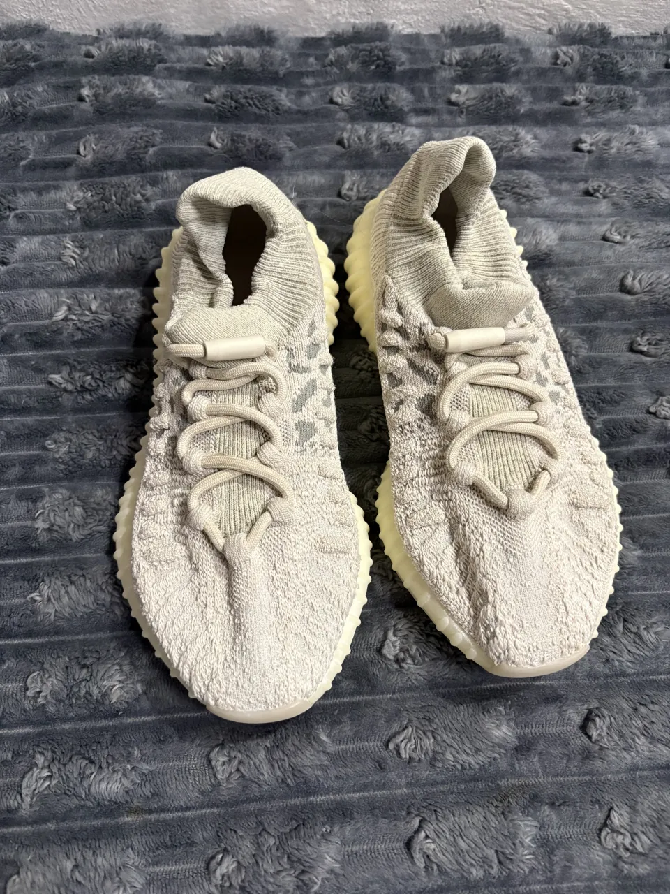 Zapatillas deportivas de tejido color gris claro con cordones blancos y suela de goma color crema.