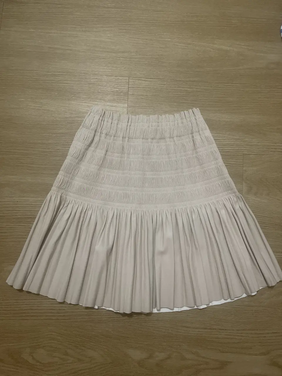 Pollera midi de color crudo, con cintura elastizada y detalle de frunces. material tipo eco cuero