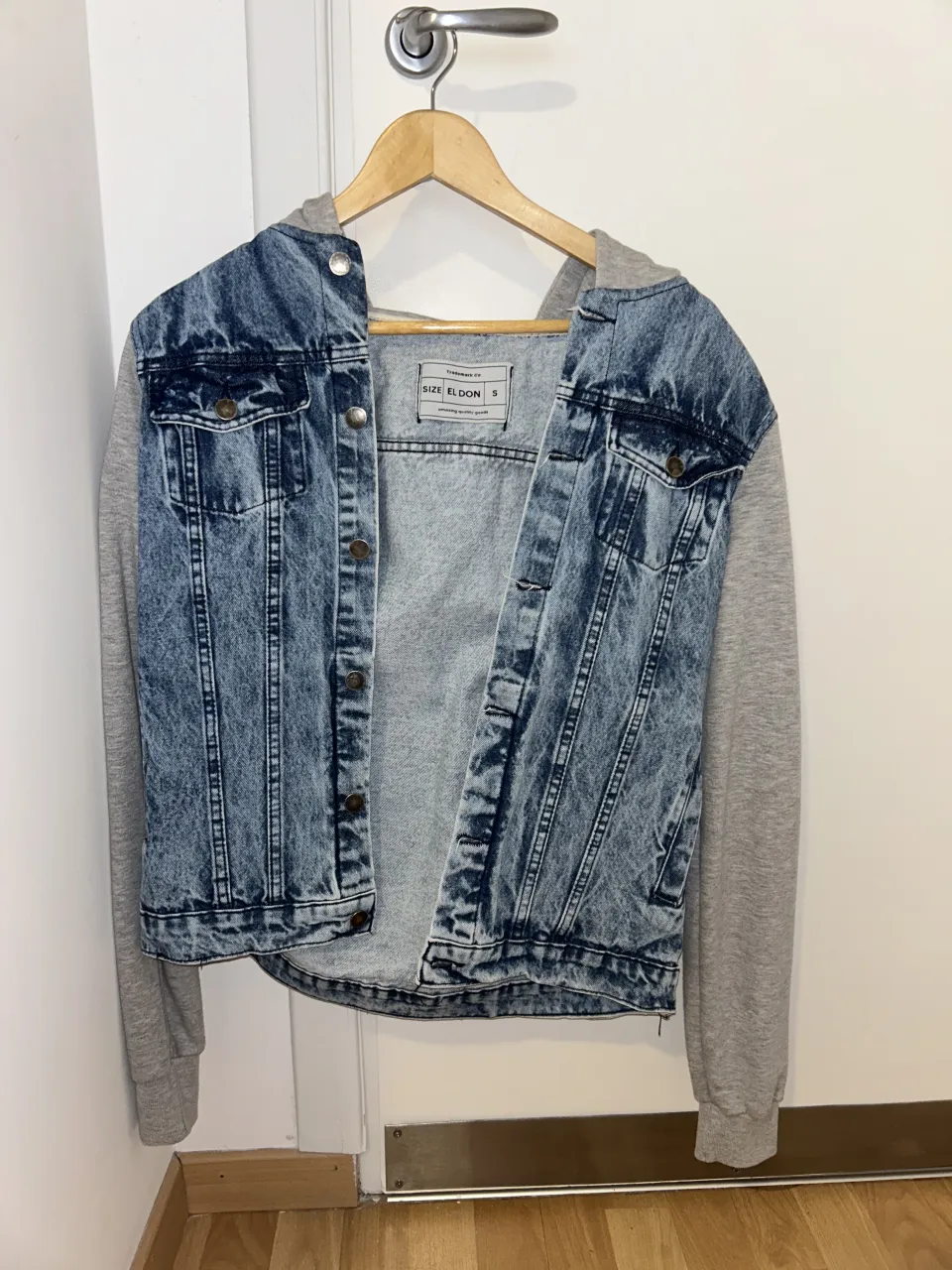 Campera de jean con mangas y capucha de algodón. Lavado desgastado y detalles de bolsillos con botones.