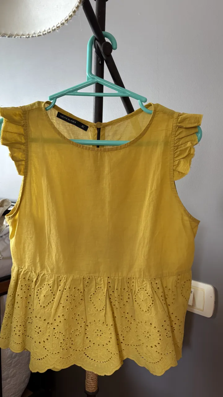 Remera amarilla con detalles de bordado y volados en las mangas.