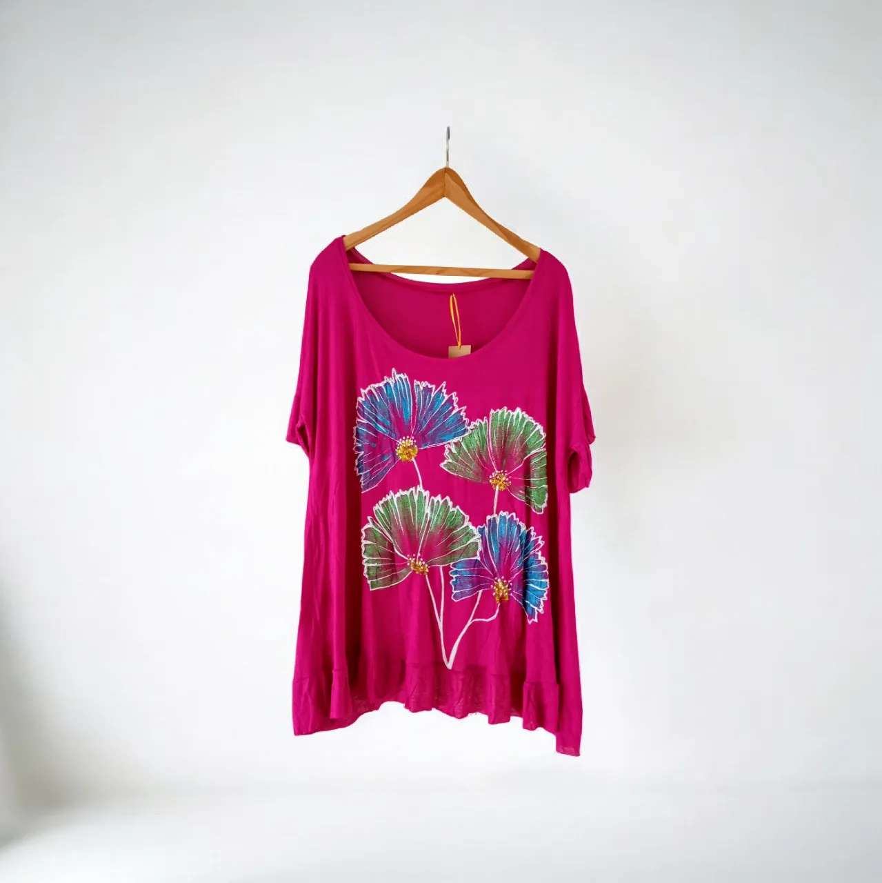 Remera fucsia con estampa de flores en tonos verdes, azules y rosas. Posee volados en el frente y en la espalda.