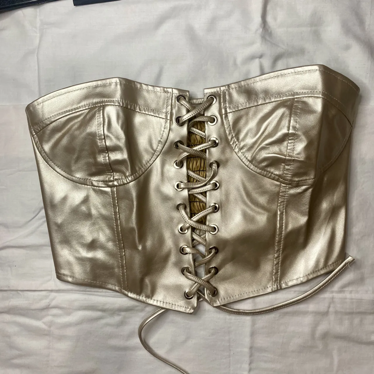 Top tipo corset plateado con cordones al frente y detalle de fruncido en la espalda.