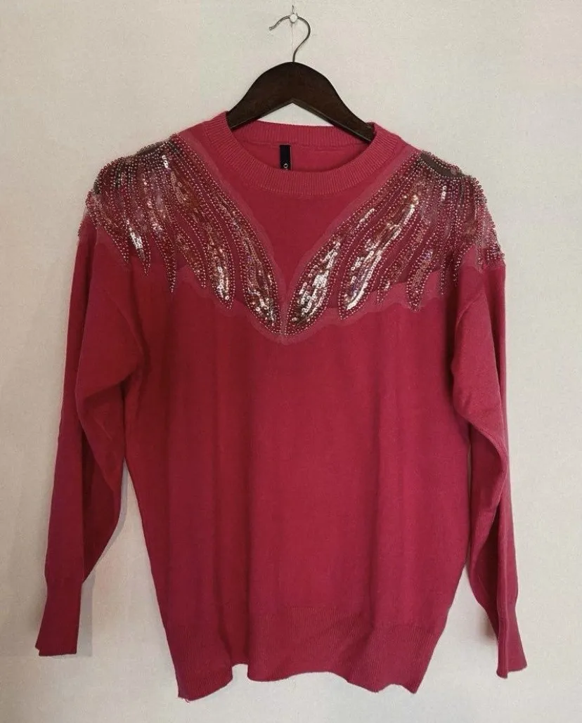 Sweater rosa con detalles de pedrería y lentejuelas en cuello y hombros.