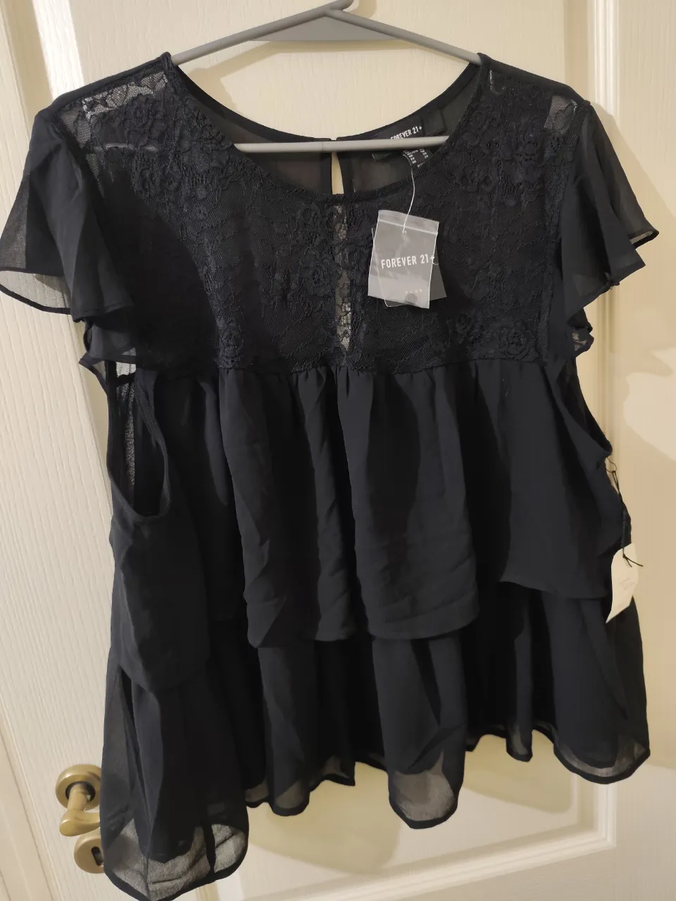 Remera negra con detalles de encaje en el busto y mangas cortas con volados. Posee doble capa de tela en la parte inferior. Talle 3X.