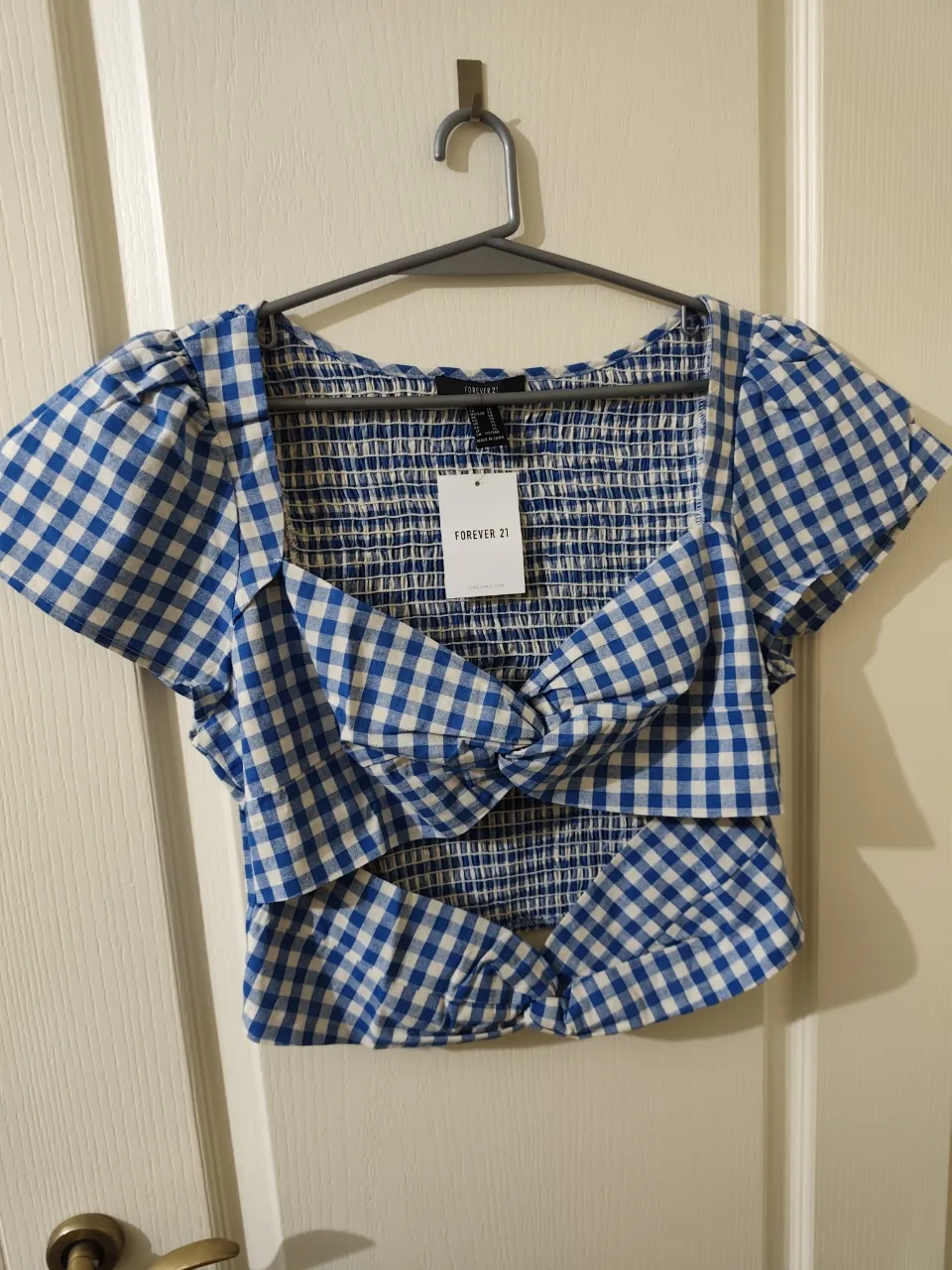 Remera corta a cuadros escoceses en azul y blanco. Posee un nudo en la parte delantera y mangas cortas abullonadas.