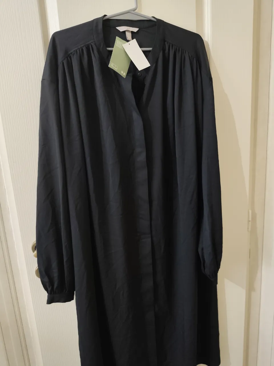 Vestido negro largo con mangas largas y cuello mao con botones. Incluye cinturón de tela para ajustar.