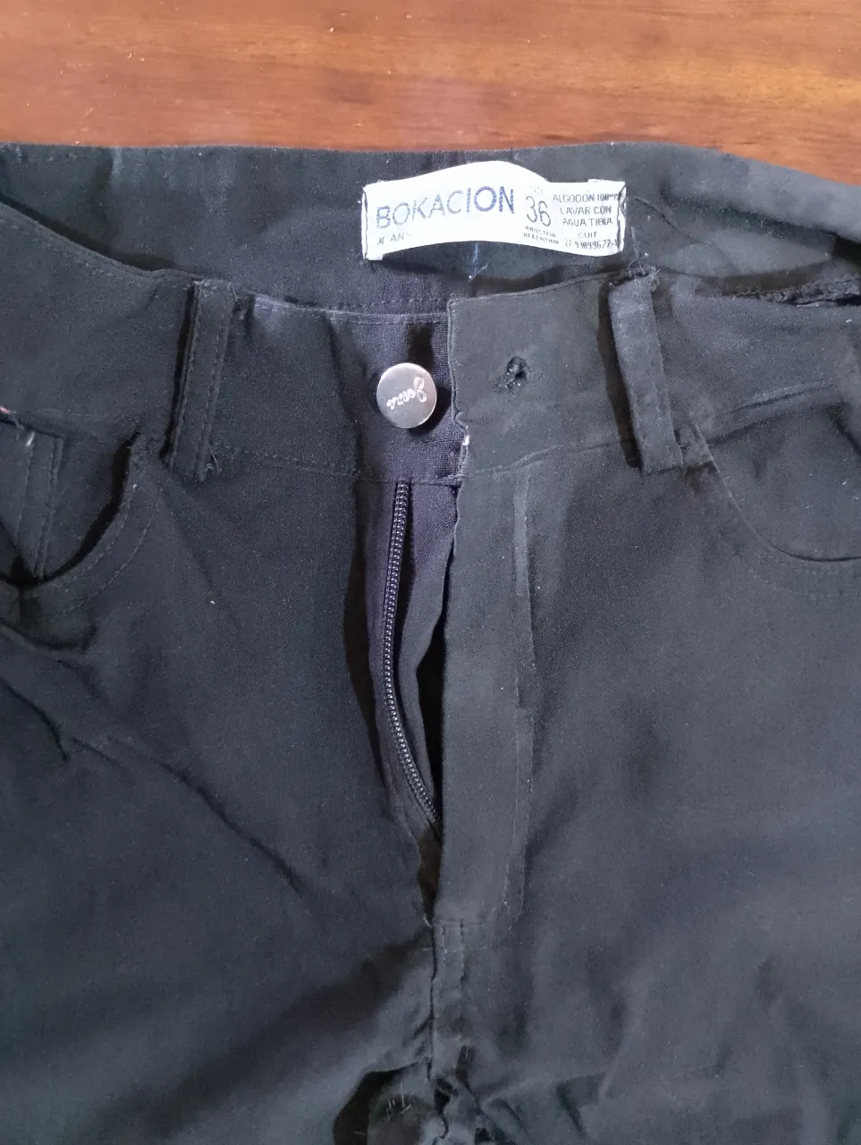 Pantalón negro con cierre y botón.