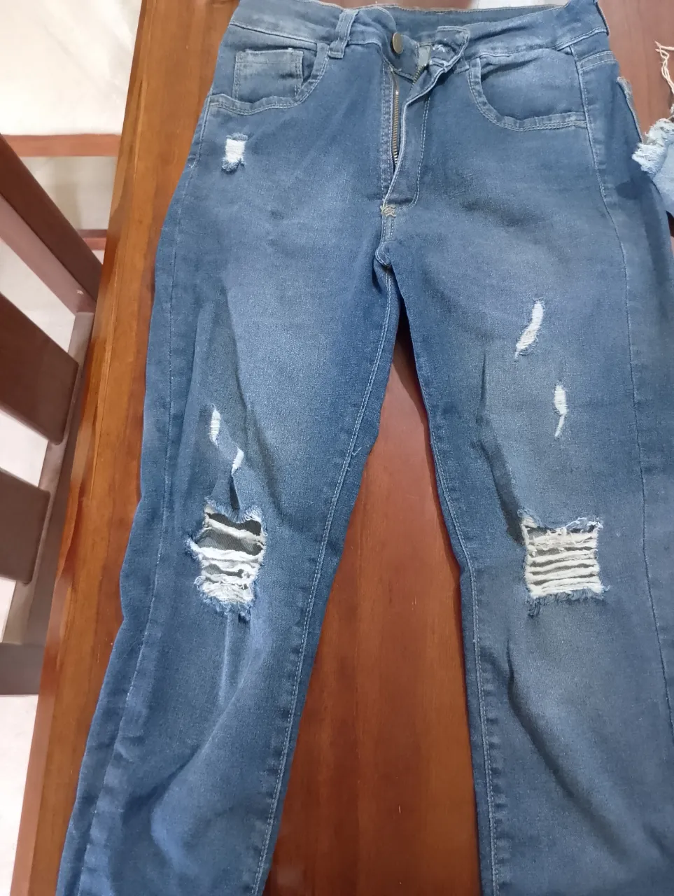 Jean de tiro alto con roturas y desgastes. Cierre y botón en la parte delantera. Bolsillos delanteros y traseros.