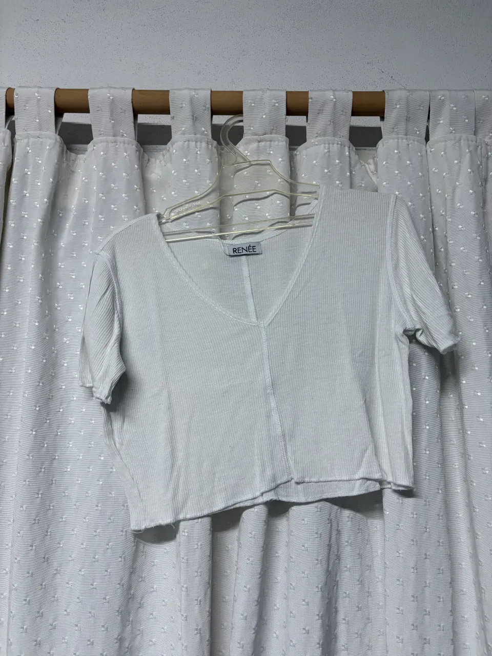 Remera blanca de manga corta con escote en V y terminación deshilachada.