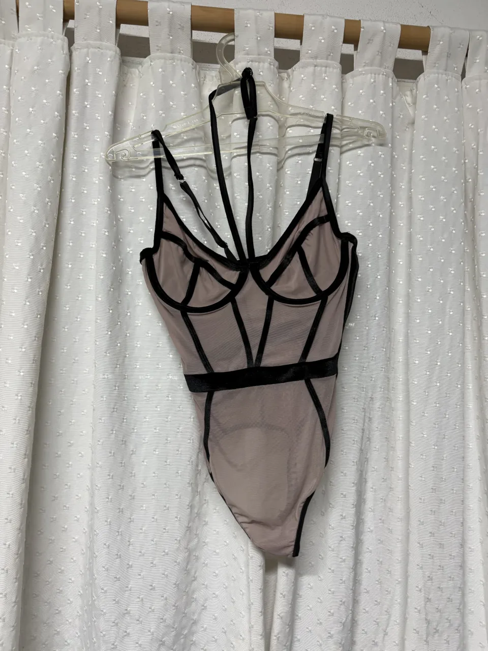 Body de encaje con tiras y detalles en negro. Breteles finos y escote pronunciado.