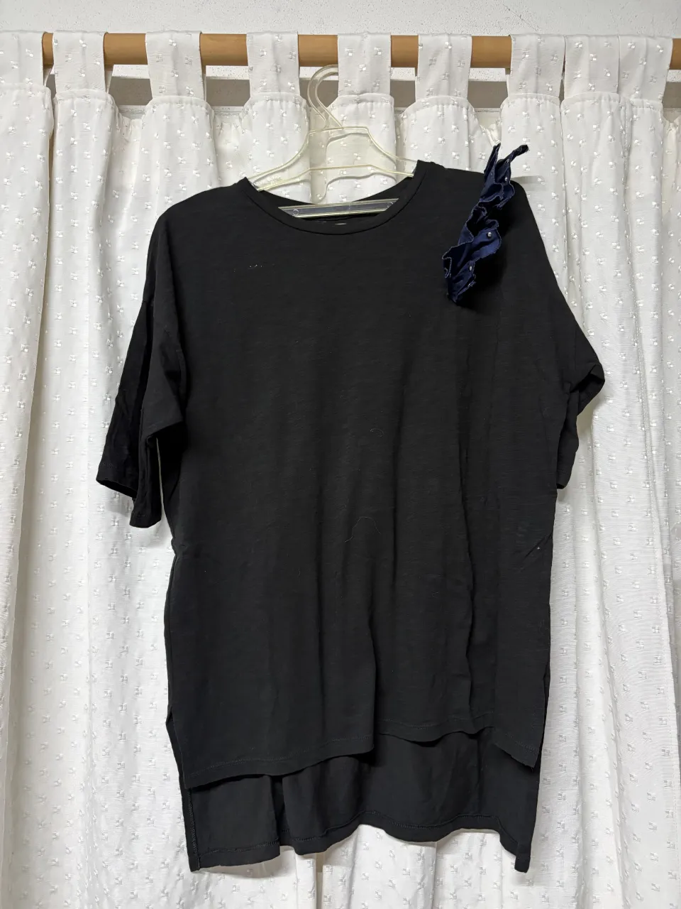 Remera negra de manga corta con detalle de volados en la manga izquierda.