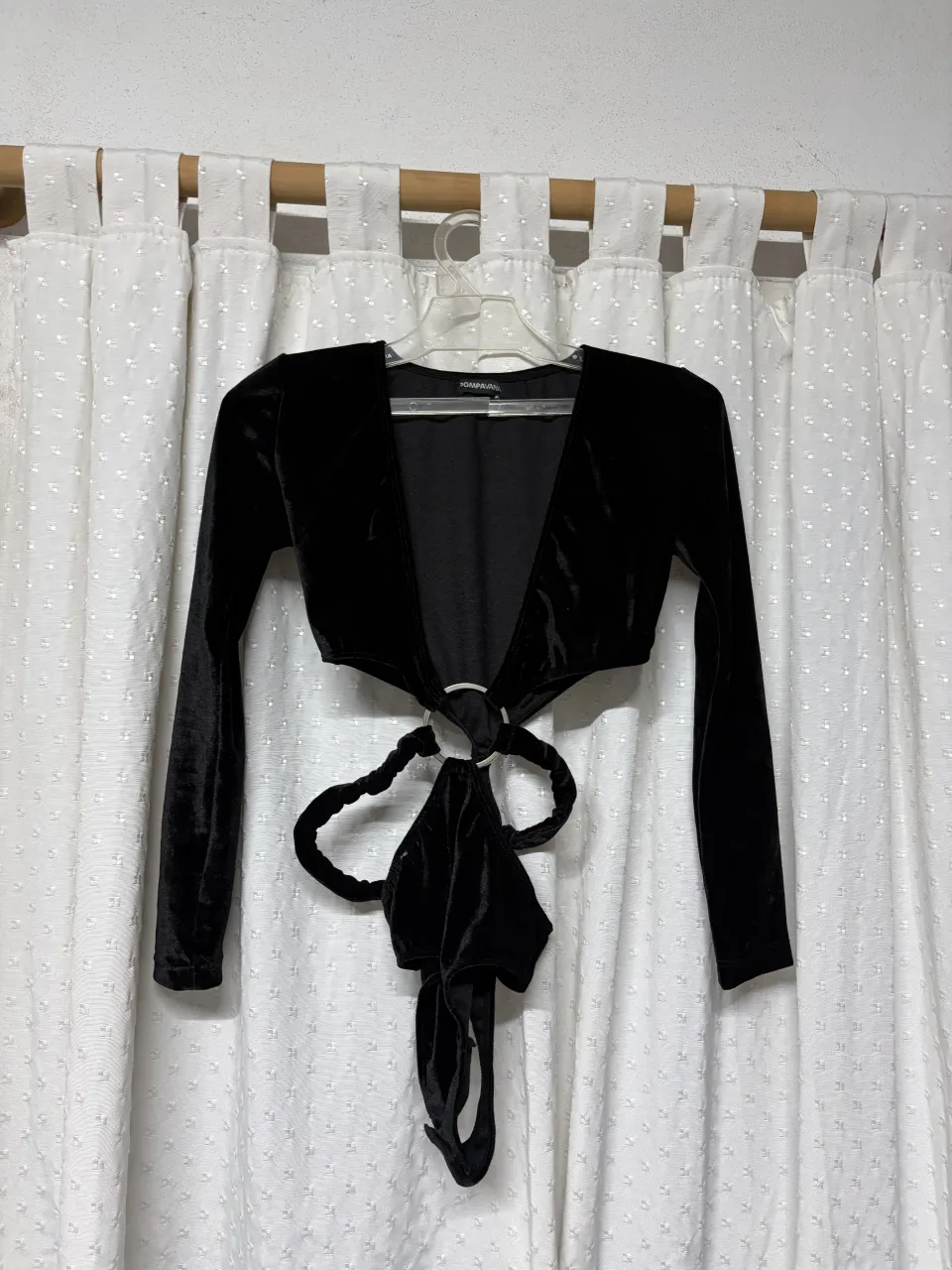 Top negro de terciopelo con escote pronunciado y mangas largas. Posee un detalle de argolla metálica en el frente y tiras para atar en la espalda.